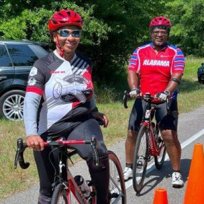 A woman and man in their 60s both sit on bicycles, lining up for a race.